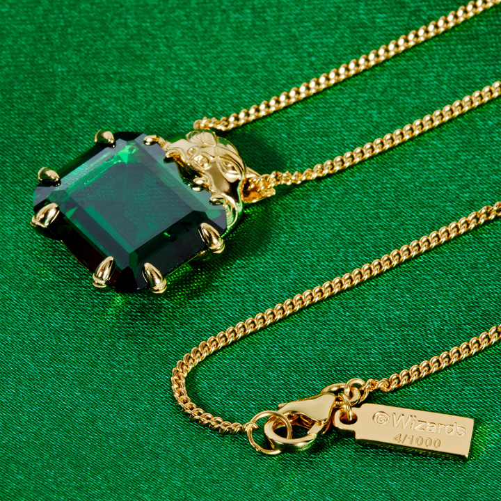 Magic: The Gathering X RockLove Mox Emerald Necklace —  Emerald set in 14K gold plated sterling silver, [context:  a gold chain necklace featuring a square-cut green gemstone pendant with gold prongs, displayed on a textured green background. A small gold tag engraved with '4/1000' is attached to the chain.]