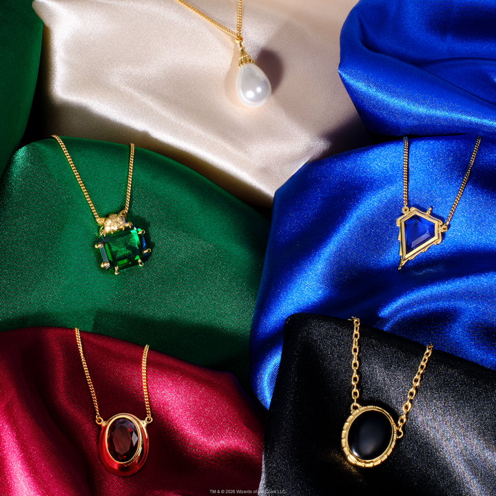 Magic: The Gathering X RockLove Mox Pearl, Sapphire, Jet, Ruby, and Emerald Necklaces — set in 14K gold
plated sterling silver, [context: Five gold pendant necklaces displayed on draped satin fabric in beige, green, blue, red, and black. The necklaces feature distinct pendants: a white pearl, a rectangular green gemstone, an oval red gemstone, and a geometric blue gemstone.]