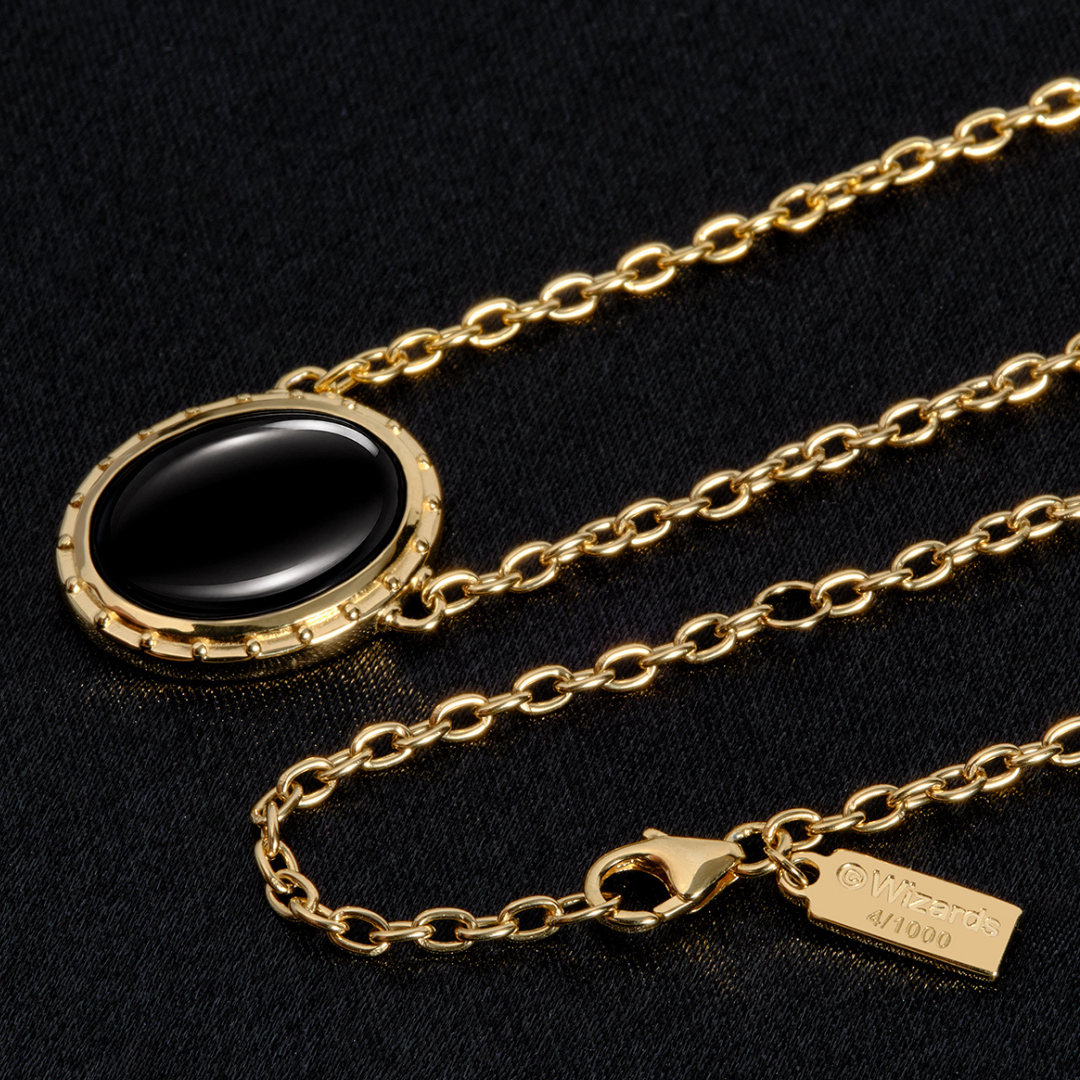 Magic: The Gathering X RockLove Mox Jet Necklace — Onyx set in 14K gold
plated sterling silver, [context: gold chain necklace with an oval black stone pendant, displayed on a textured black background. The pendant has a gold bezel setting, and a small gold tag on the clasp reads 4/1000.]