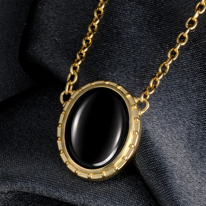 Magic: The Gathering X RockLove Mox Jet Necklace — Onyx set in 14K gold
plated sterling silver, [context: gold-tone oval pendant necklace with a smooth black cabochon stone, displayed on a dark textured fabric background.]