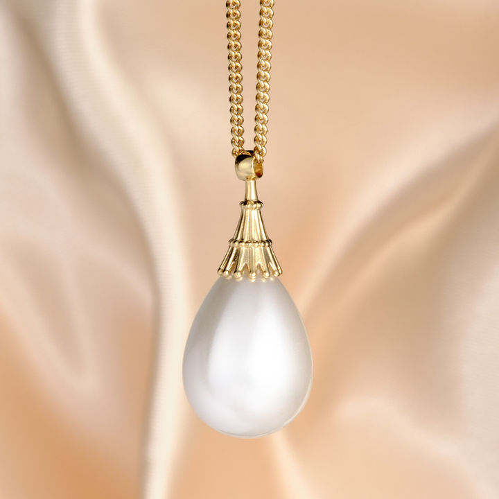 Magic: The Gathering X RockLove Mox Pearl Necklace — Pearl set in 14K gold
plated sterling silver, [context: a gold teardrop pendant necklace with a smooth, lustrous white pearl-like drop, suspended from a gold ball chain against a soft beige satin fabric background.]