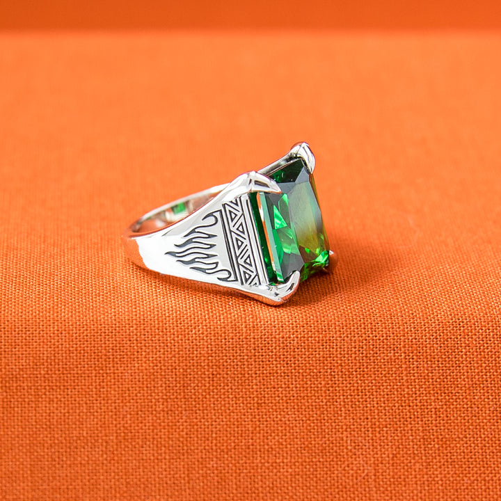 Silver ring with a green gemstone on an orange background