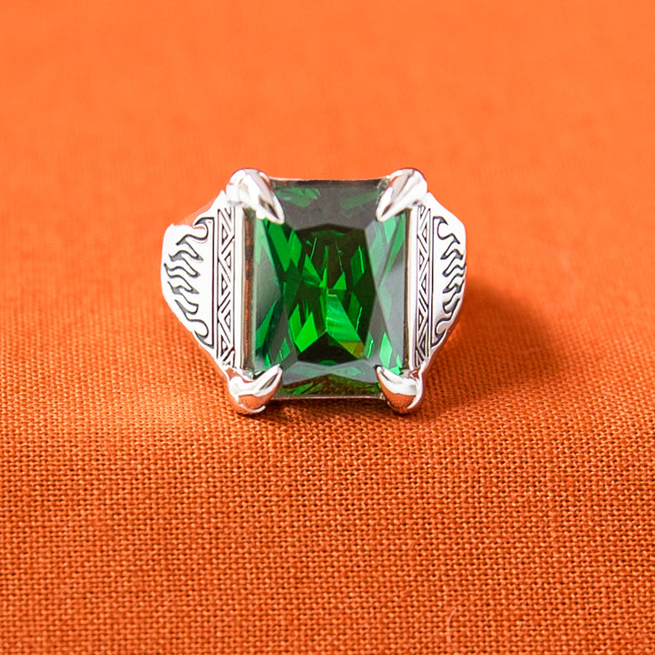 Silver ring with a green gemstone on an orange fabric background